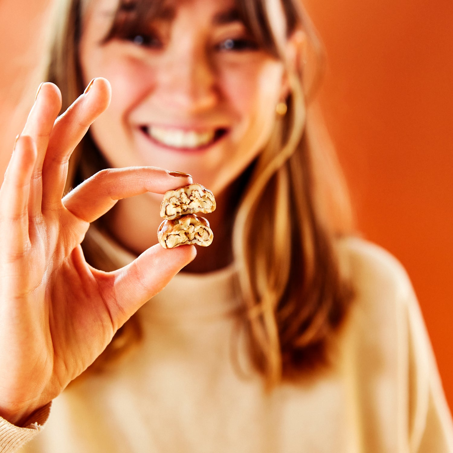 Femme tenant un noix de pécan enrobée coupée en deux